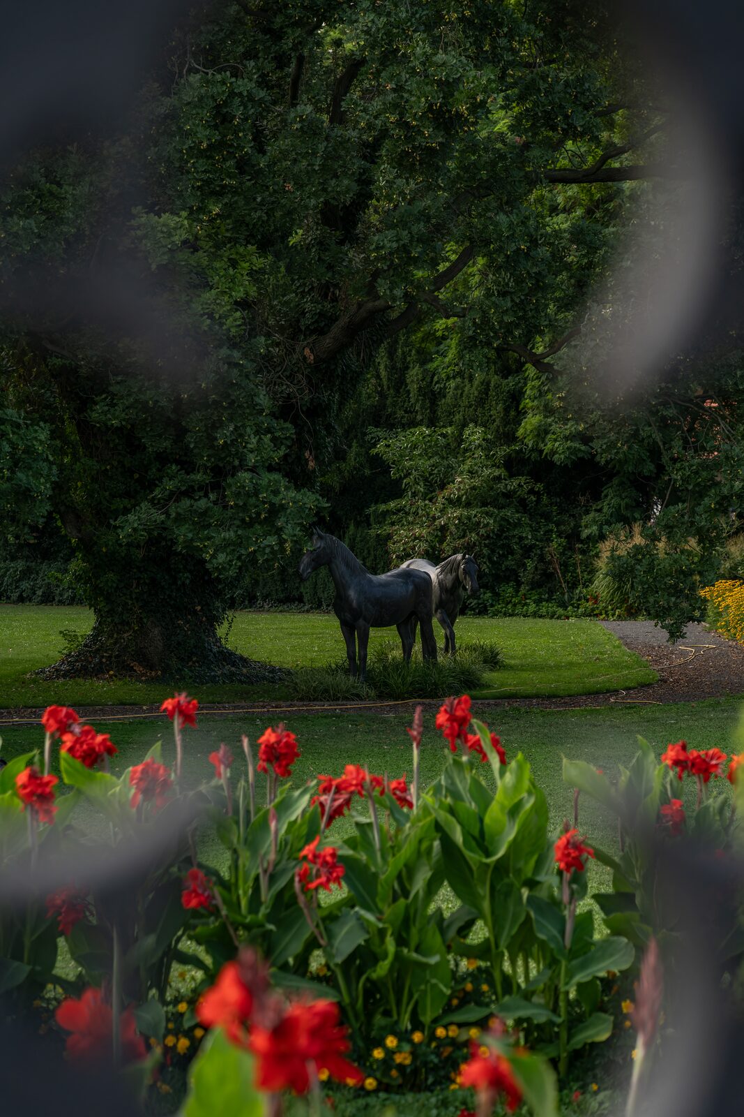 Statue de cheval dans les jardins du palais Fürstenberg (Prague), derrière des fleurs rouges