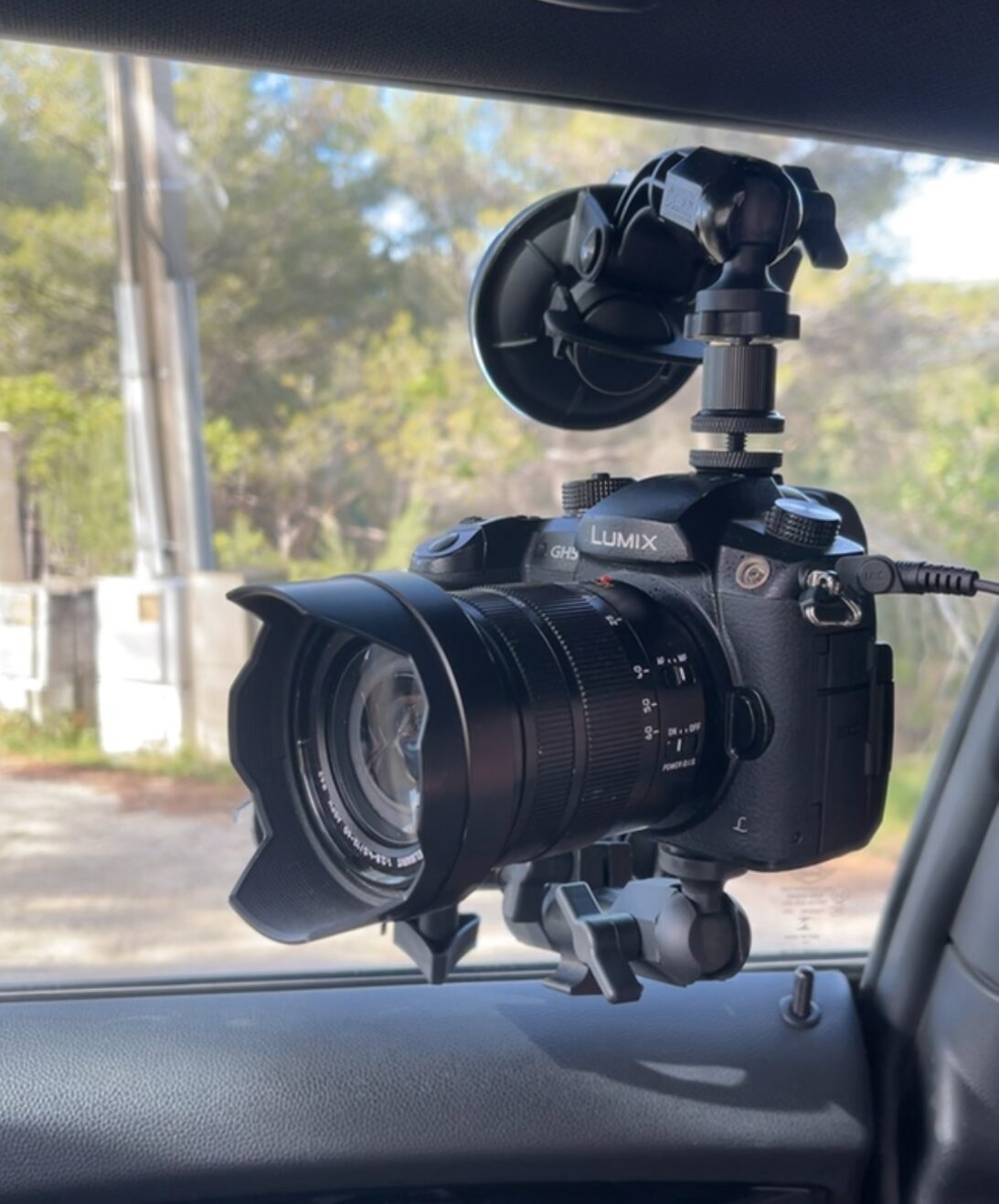 Ancien Panasonic Lumix GH5 fixé par ventouse sur une vitre, à l'intérieur d'une voiture